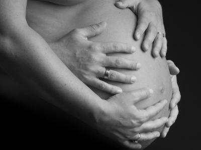 Zwangere buik met handen van de moeder en vader erover